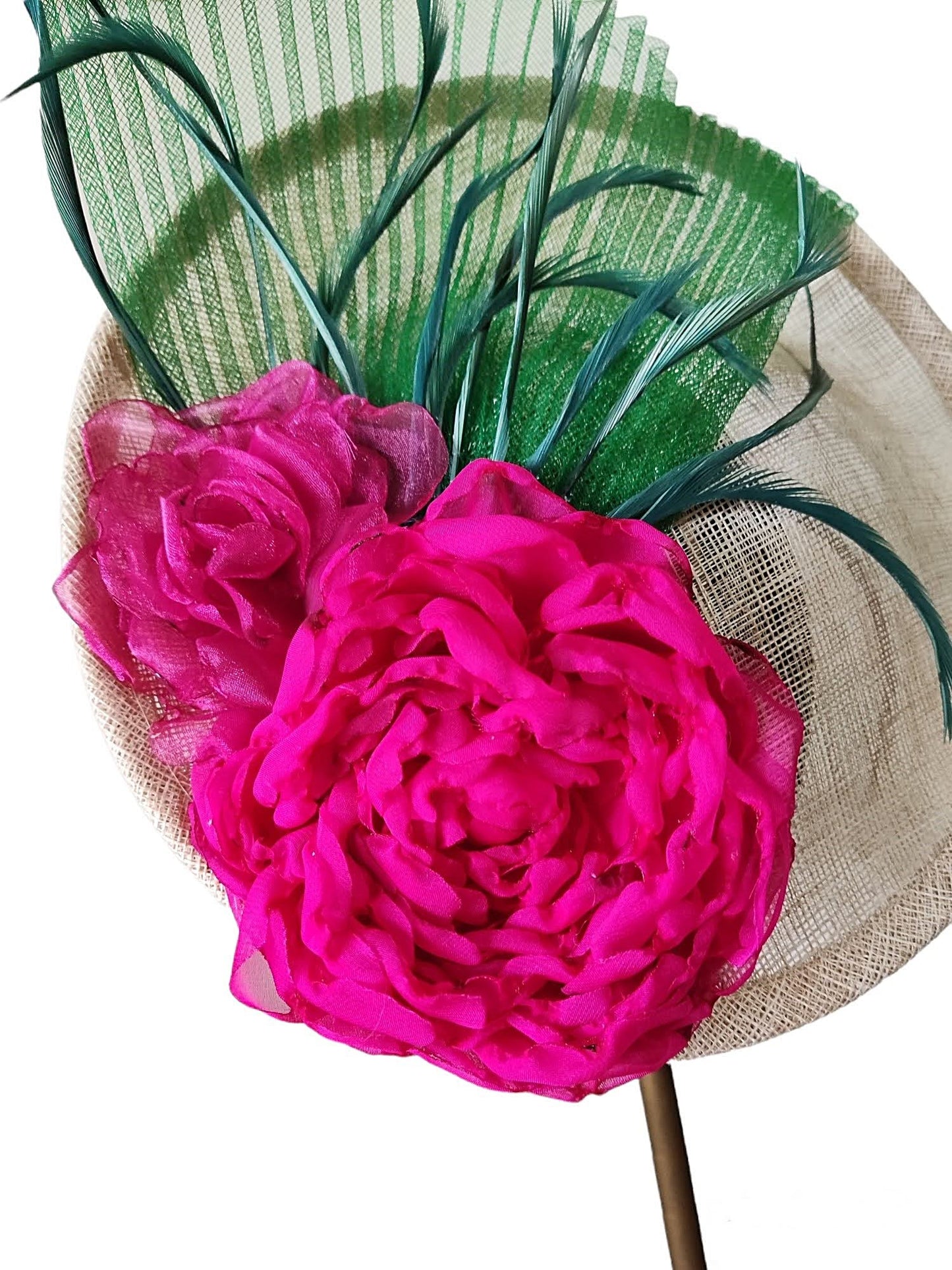 Primer plano de la decoración del tocado, detallando las flores fucsia, plumas y crinolina