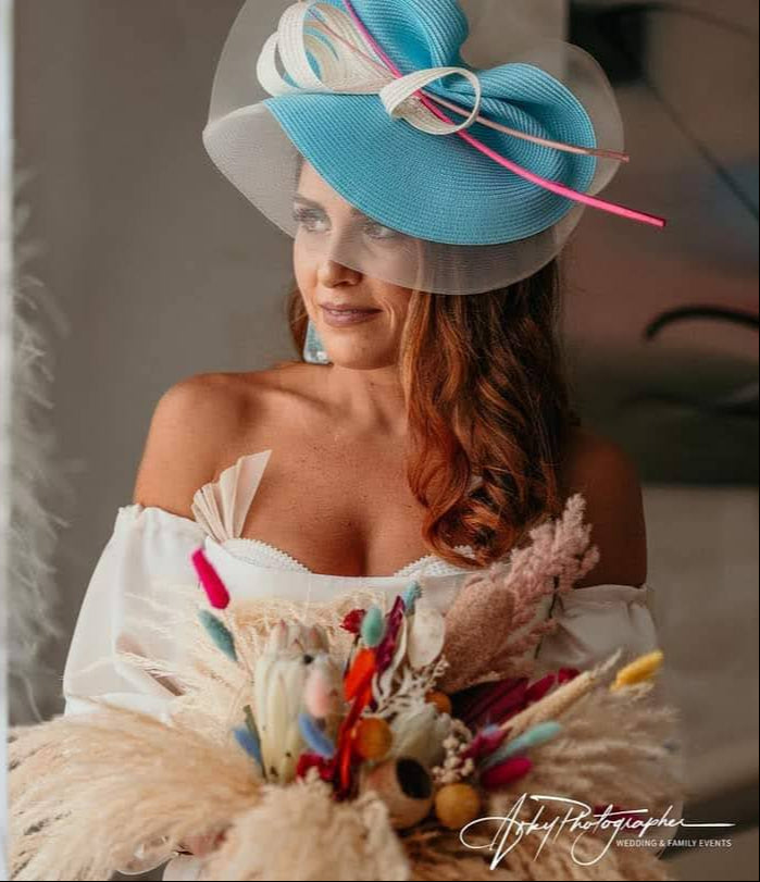 Clienta usando sombrero de ala ancha turquesa y blanco como complemento de look nupcial.