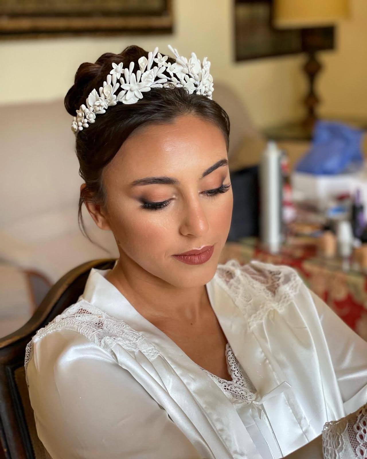 Vista de una novia preparándose para su boda, luciendo la tiara blanca con flores y pistilos de porcelana