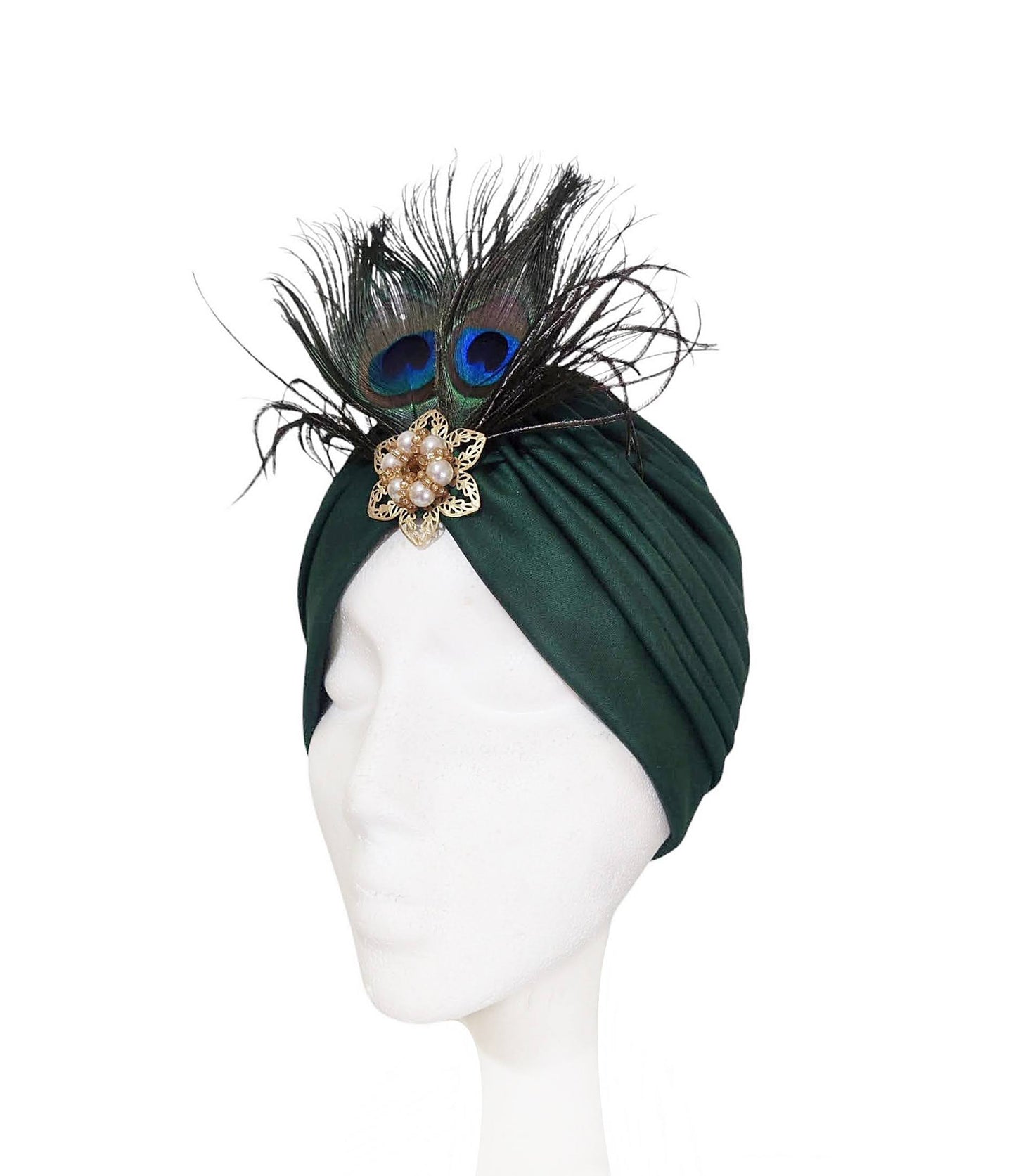 Vista de medio perfil del turbante verde oscuro con plumas de pavo real.