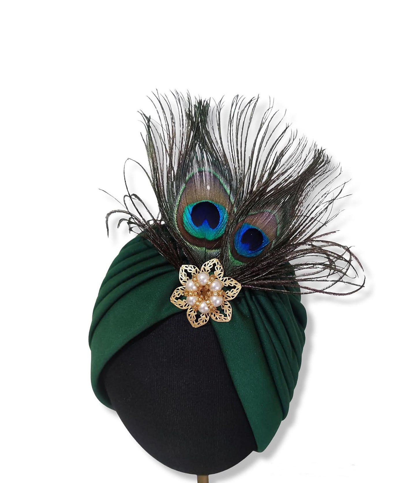 Primer plano del penacho de plumas de pavo real en el turbante verde oscuro.