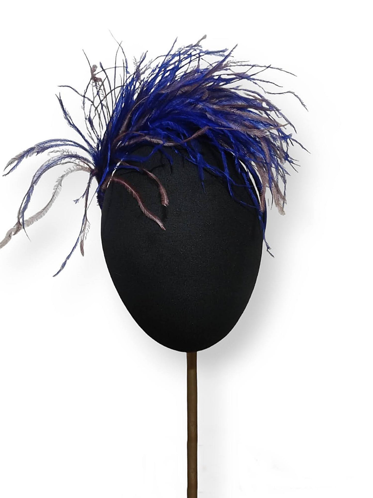 Tocado con plumas en royal y malva envejecido sobre cabeza de maniquí.