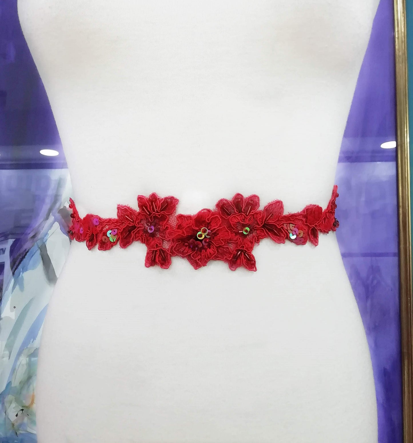 Fajín de encaje rojo bordado colocado en maniquí, ideal para bodas.