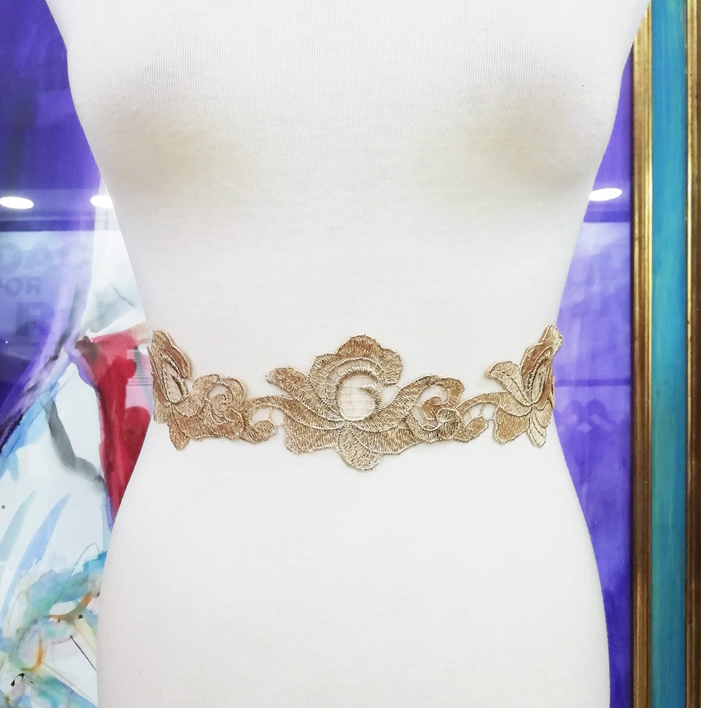 Cinturón de encaje dorado colocado en un maniquí.