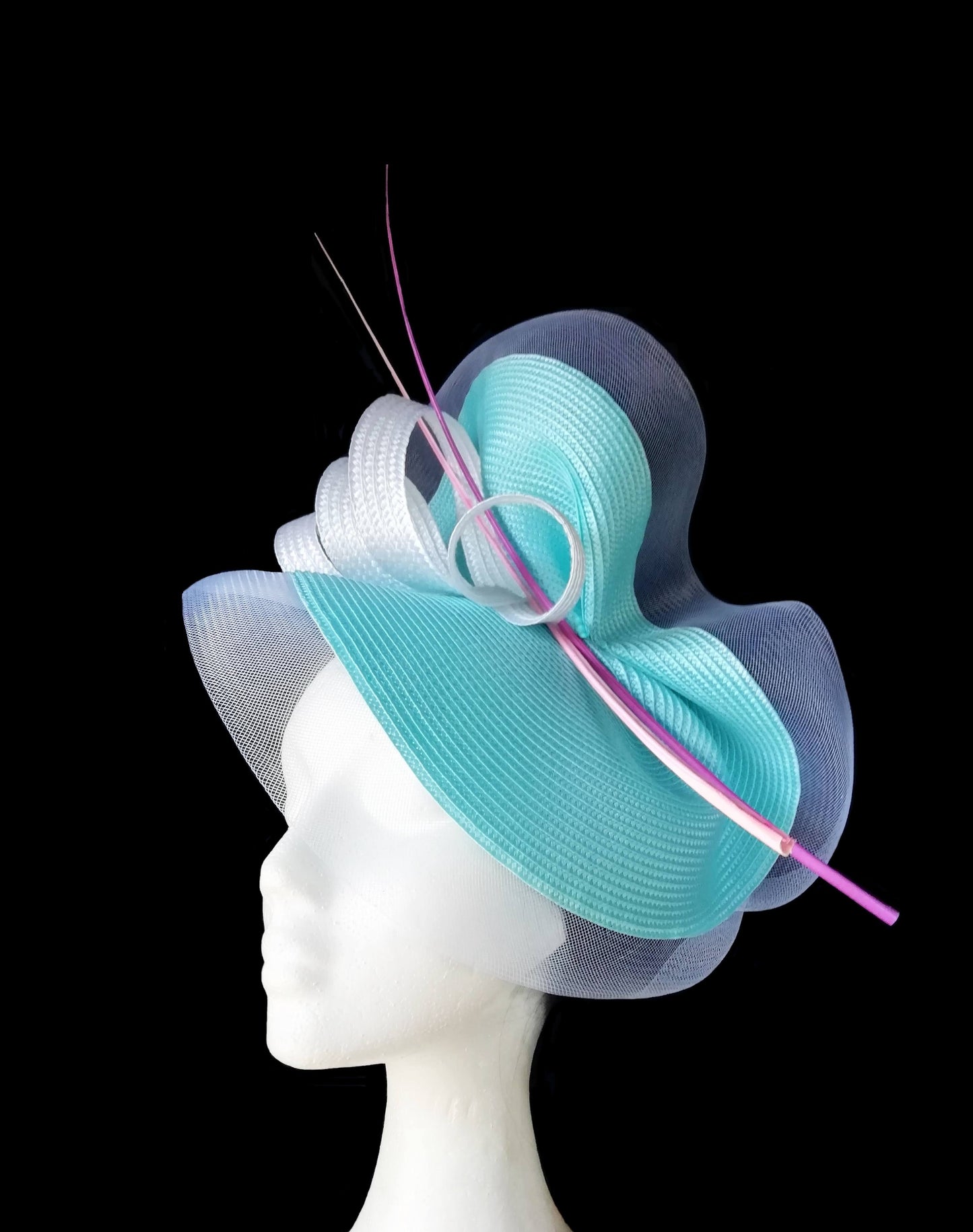 Vista de medio perfil del sombrero turquesa y blanco del lado que enmarca el rostro
