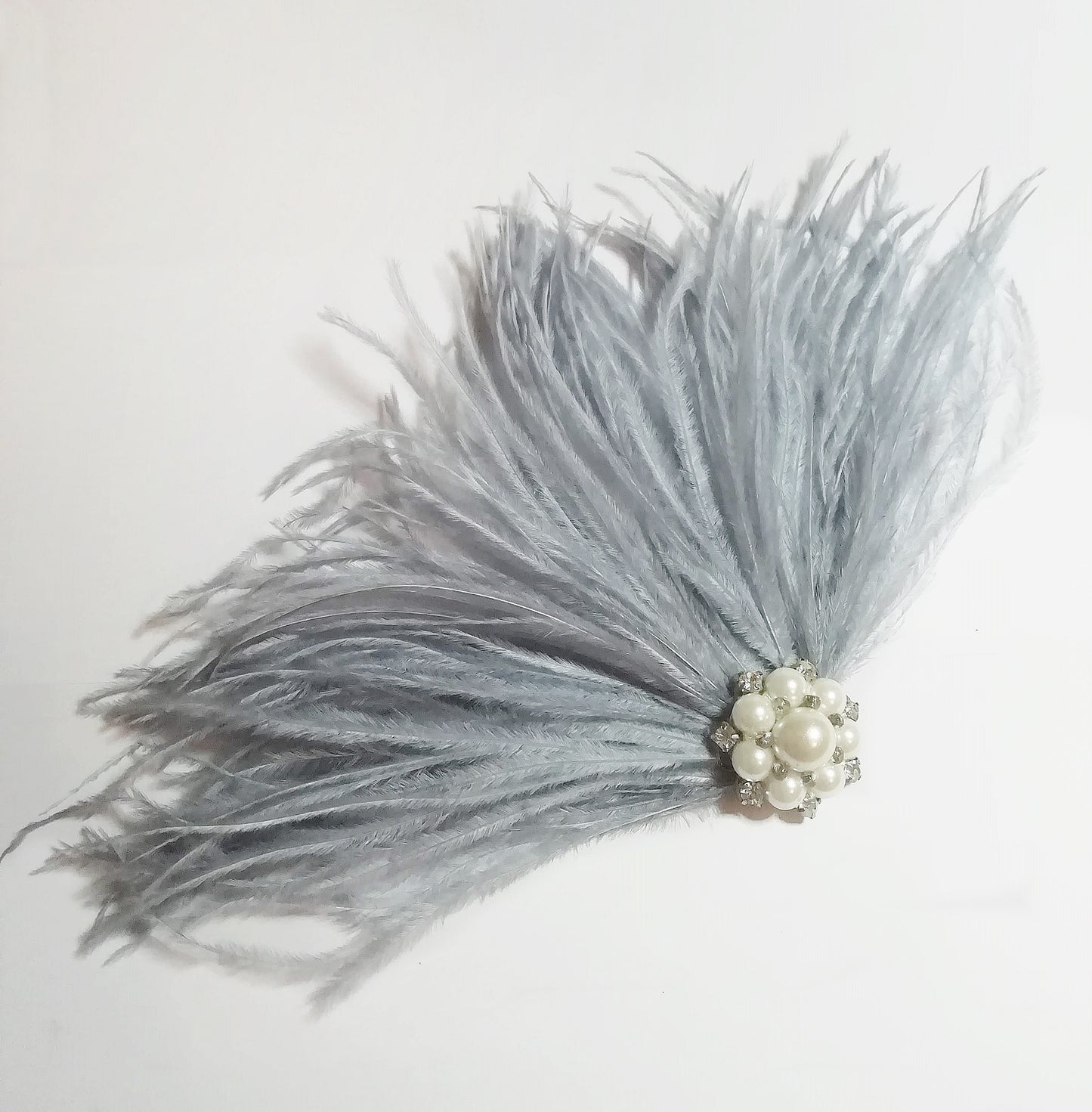 Tocado con plumas gris plata, detalle del broche con perlas y cristales.