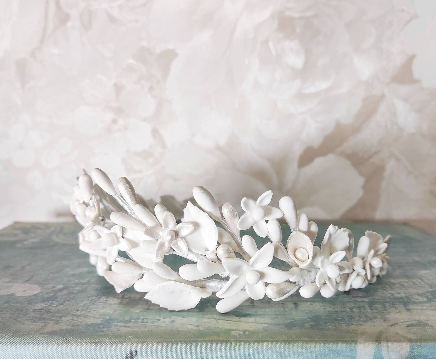 Primer plano del lado izquierdo de la tiara blanca, mostrando detalles de flores y pistilos de porcelana