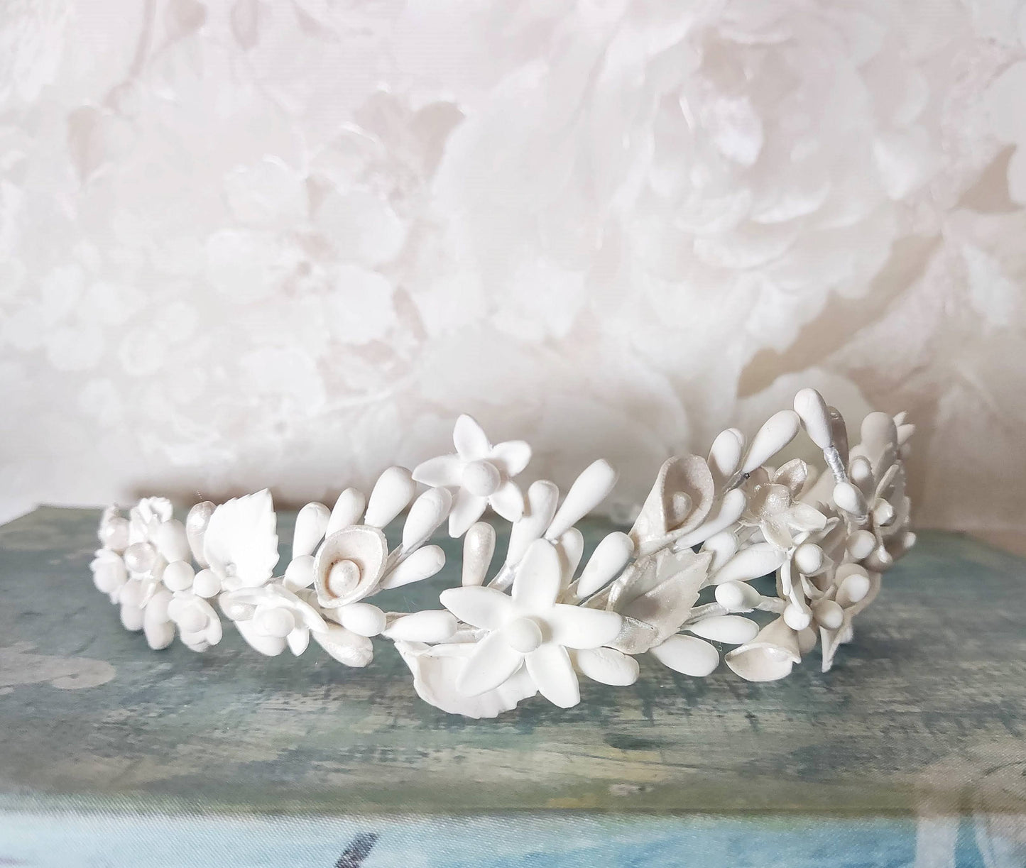 Primer plano del lado derecho de la tiara blanca, mostrando flores, hojas y pistilos de porcelana