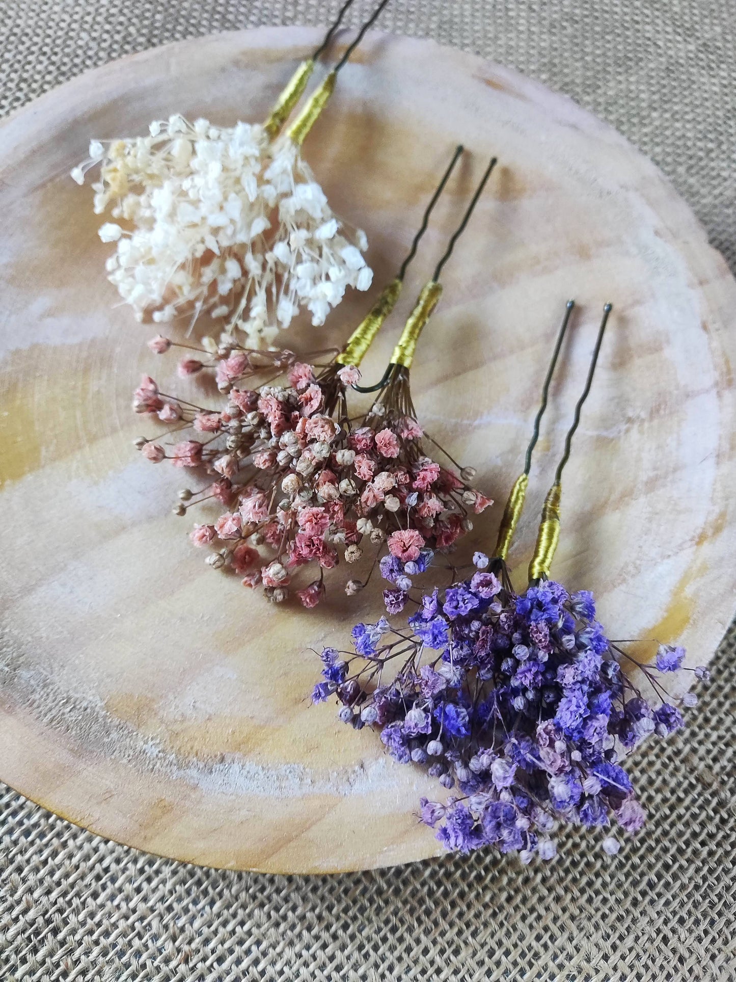 Tres horquillas con paniculata morada, rosa, y marfil sobre una base de madera