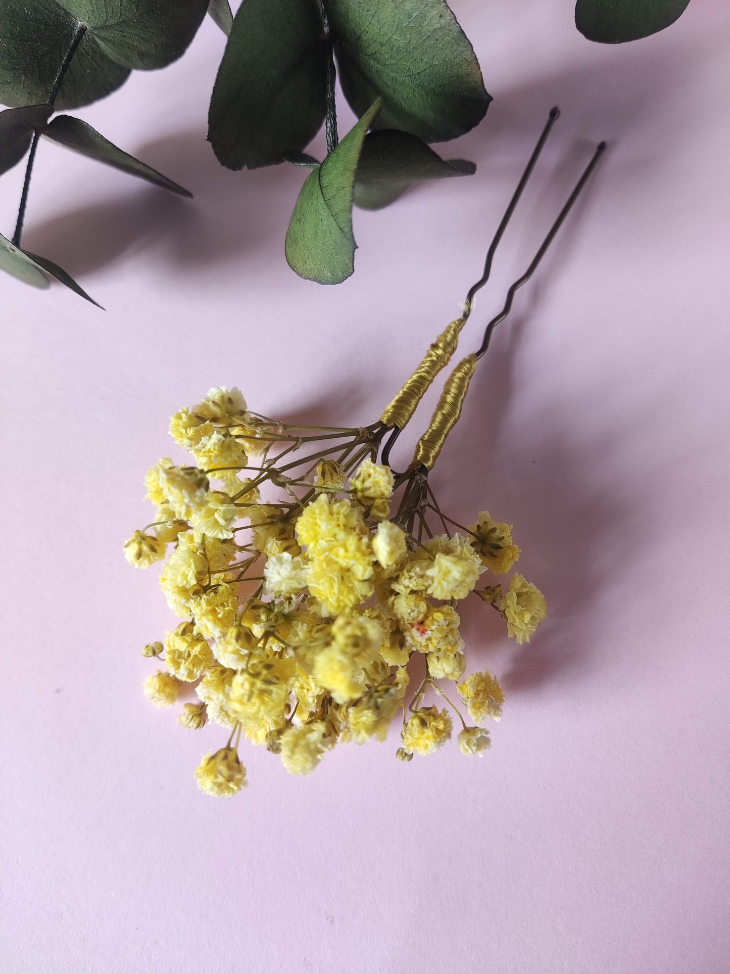 Horquilla con paniculata amarilla en detalle lateral sobre fondo rosa con rama eucalipto