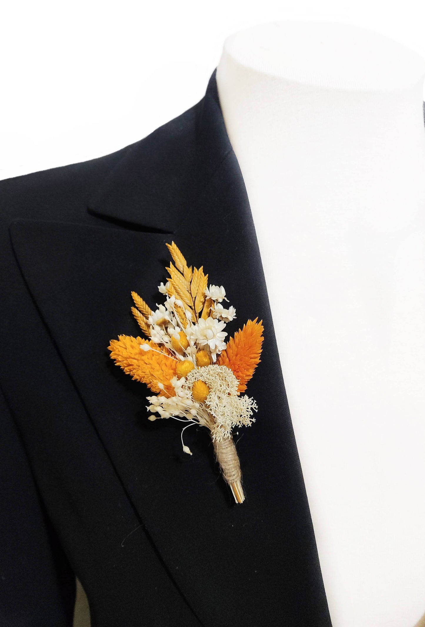 Boutonniere floral naranja y marfil colocado en la solapa de una chaqueta negra