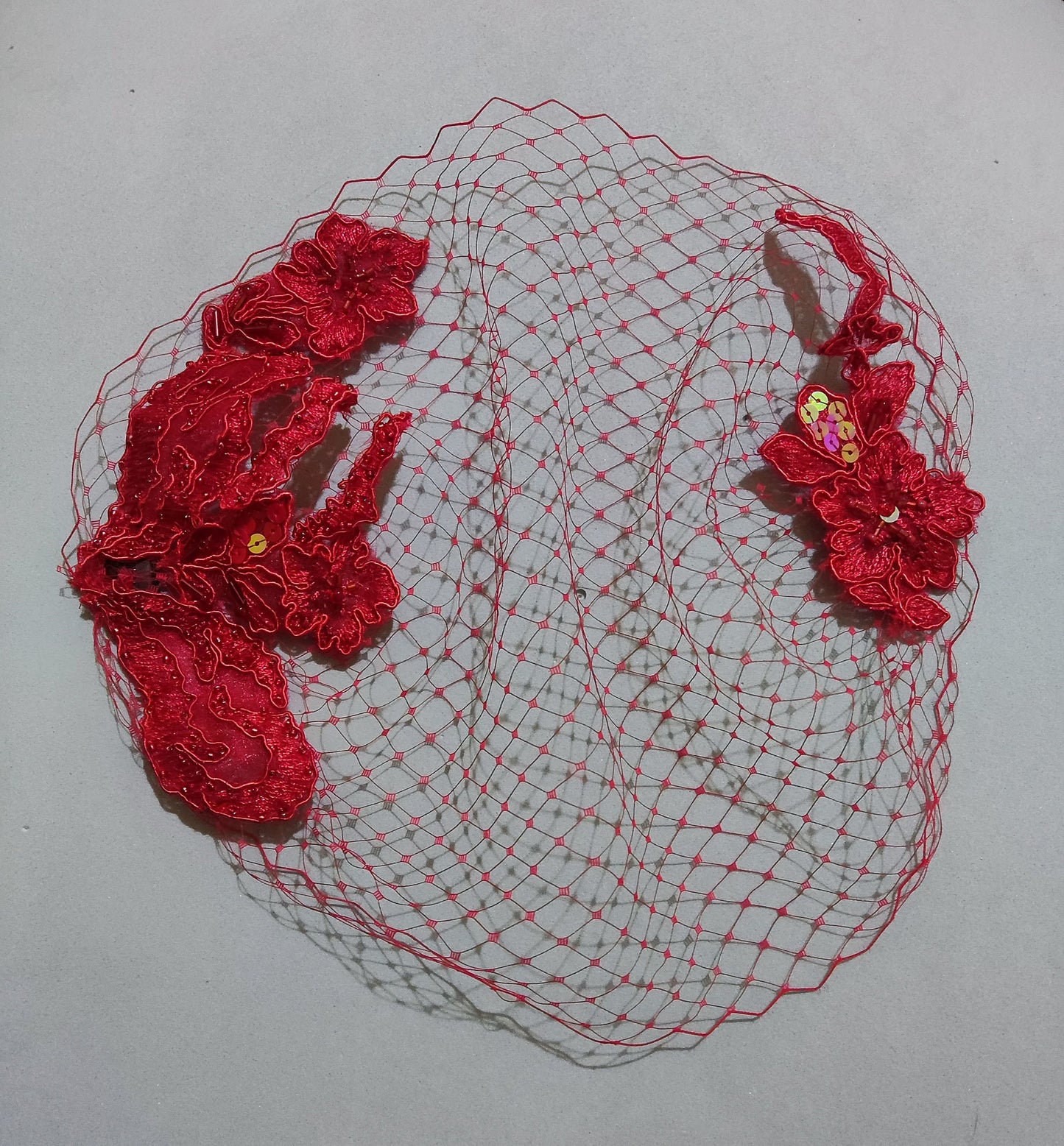 Velo de rejilla rojo extendido sobre una superficie gris.