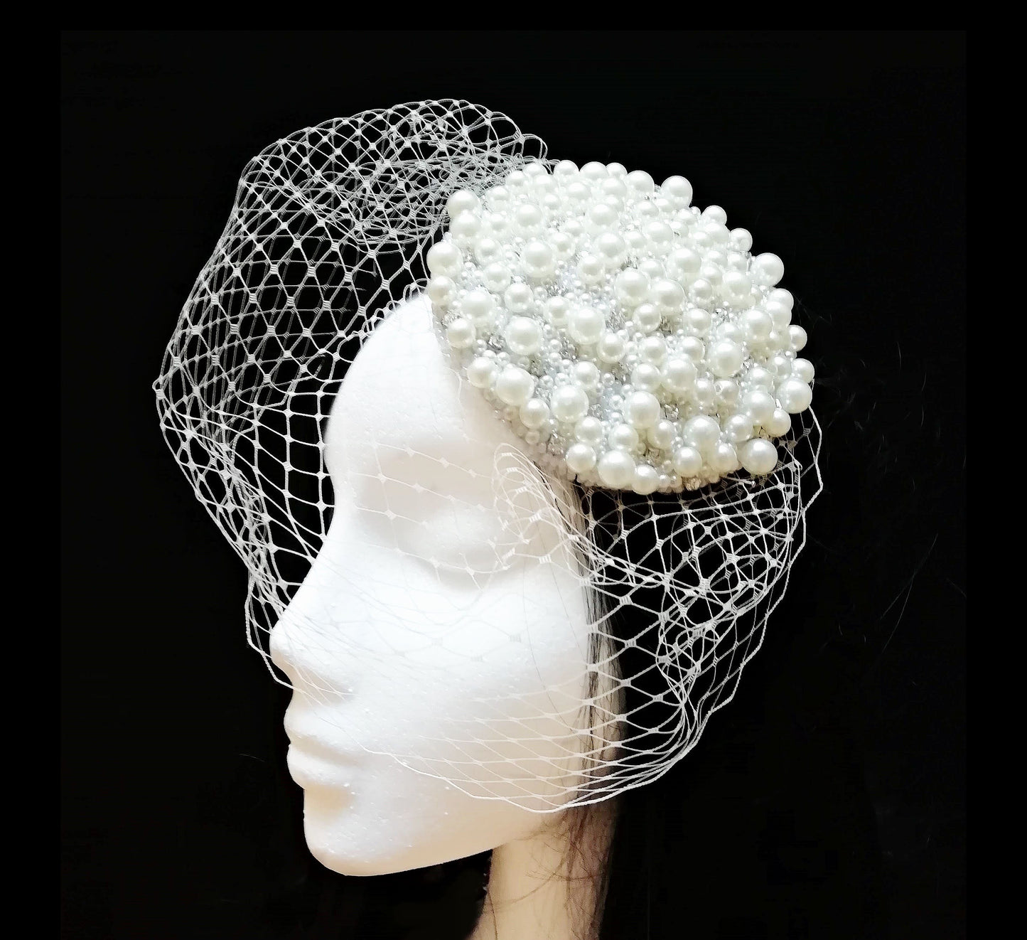 Tocado de novia en marfil con perlas y velo sobre maniquí.