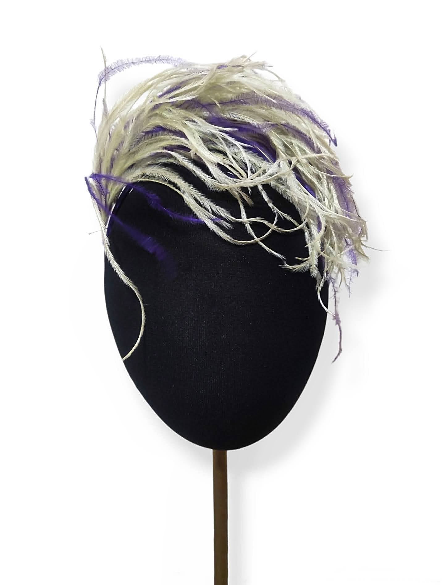 Tocado con plumas de avestruz en verde pastel y morado sobre maniquí.