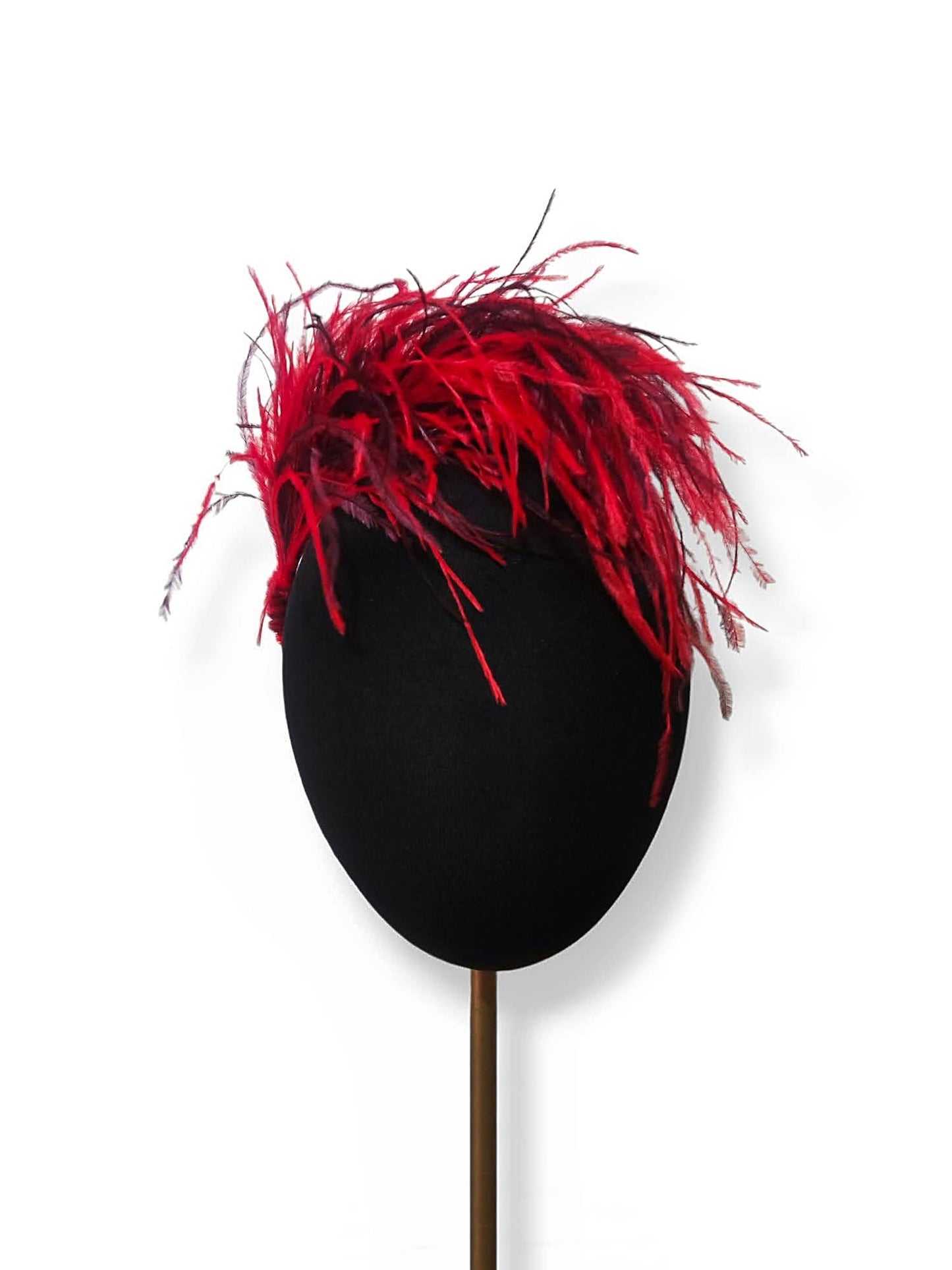 Tocado de fiesta con plumas en rojo y burdeos sobre maniquí.