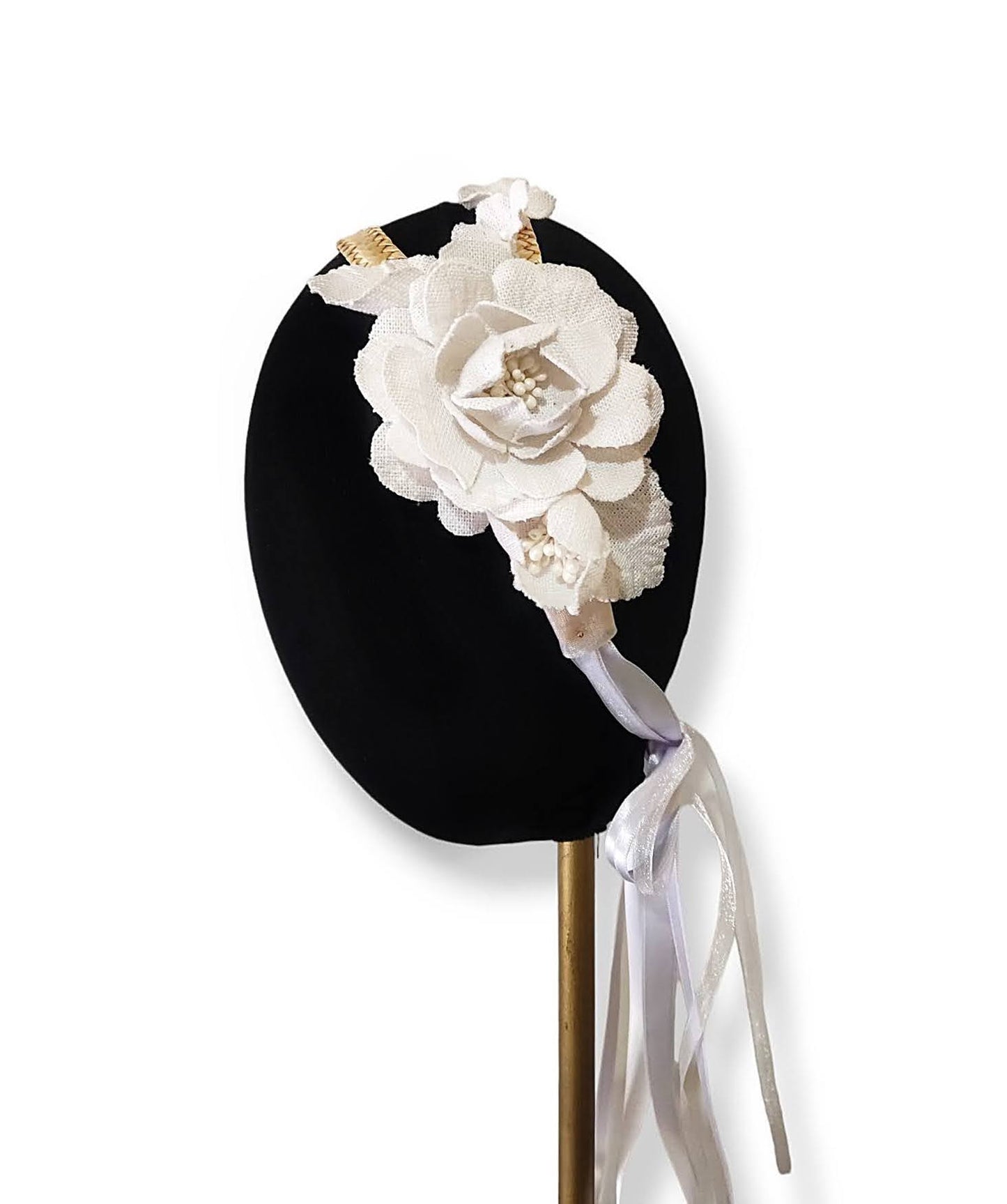 Vista de una diadema con flores blancas y lazos para fijarla sobre un maniquí