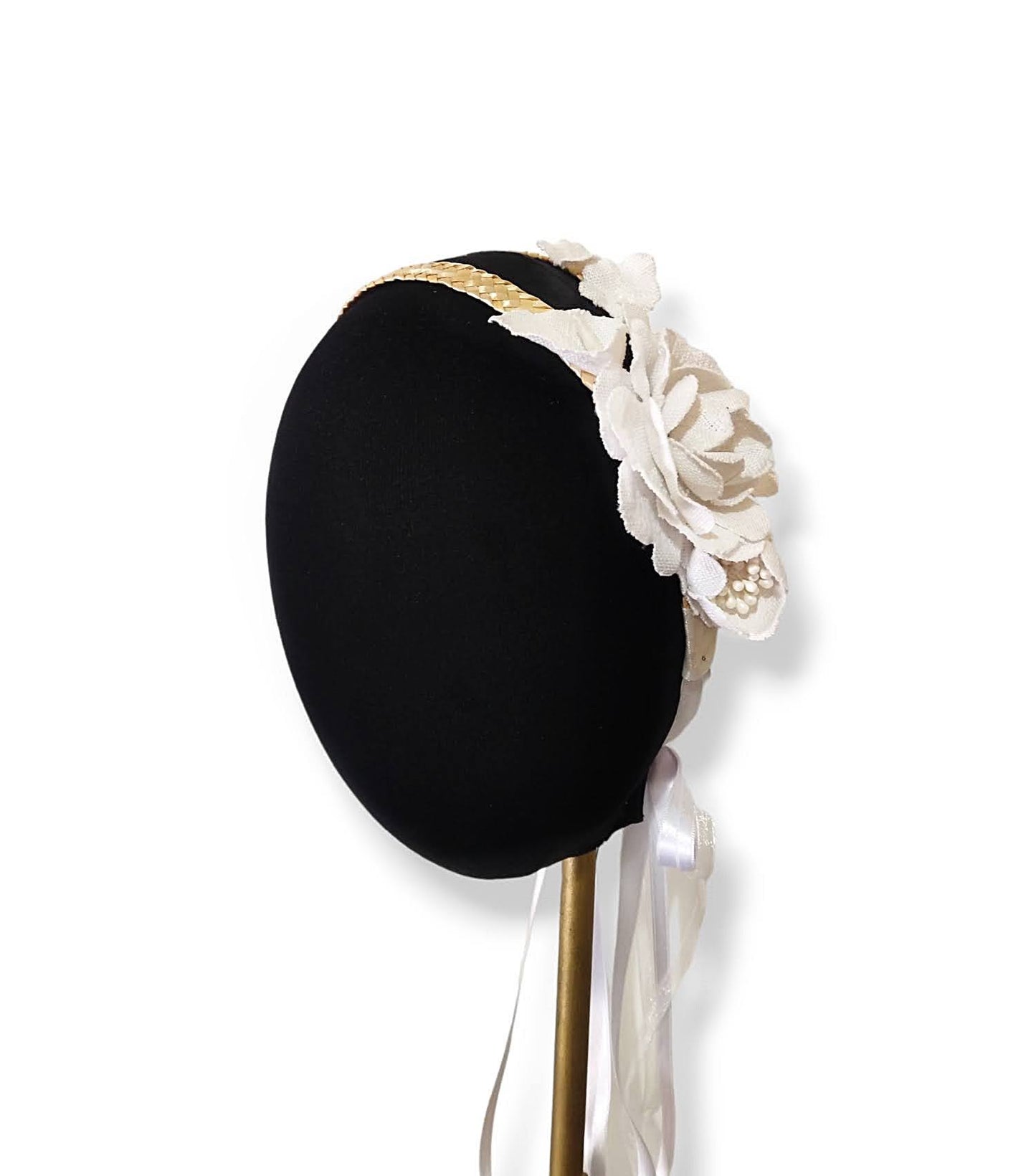 vista lateral de una diadema de paja con flores blancas sobre un maniquí
