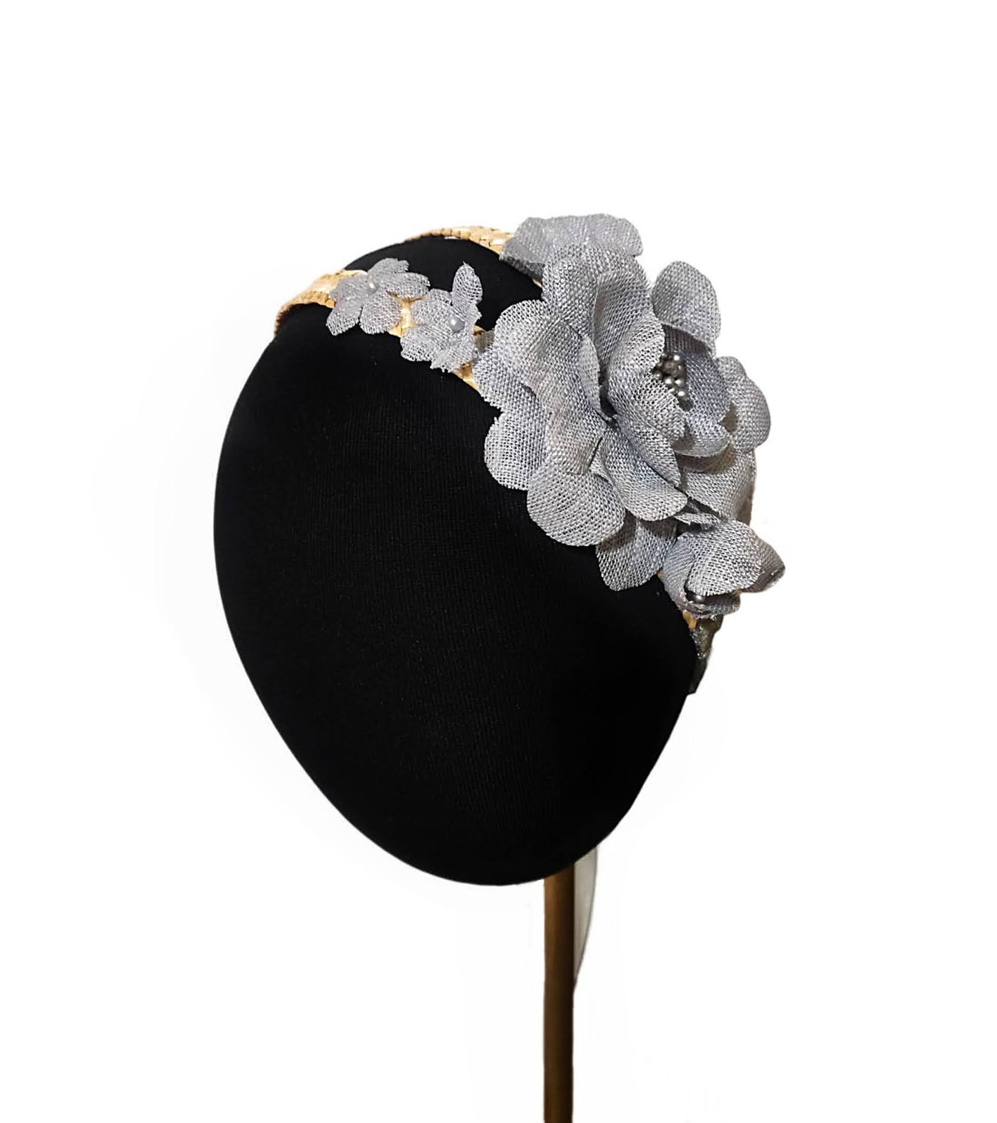Primer plano de flores grises en diadema de paja sobre cabeza de maniquí.