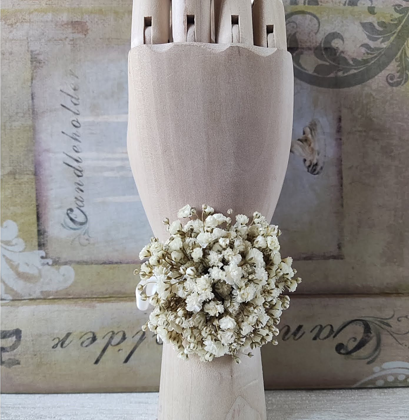 Corsage blanco de paniculata colocado en la muñeca, sobre mano de madera en posición vertical.