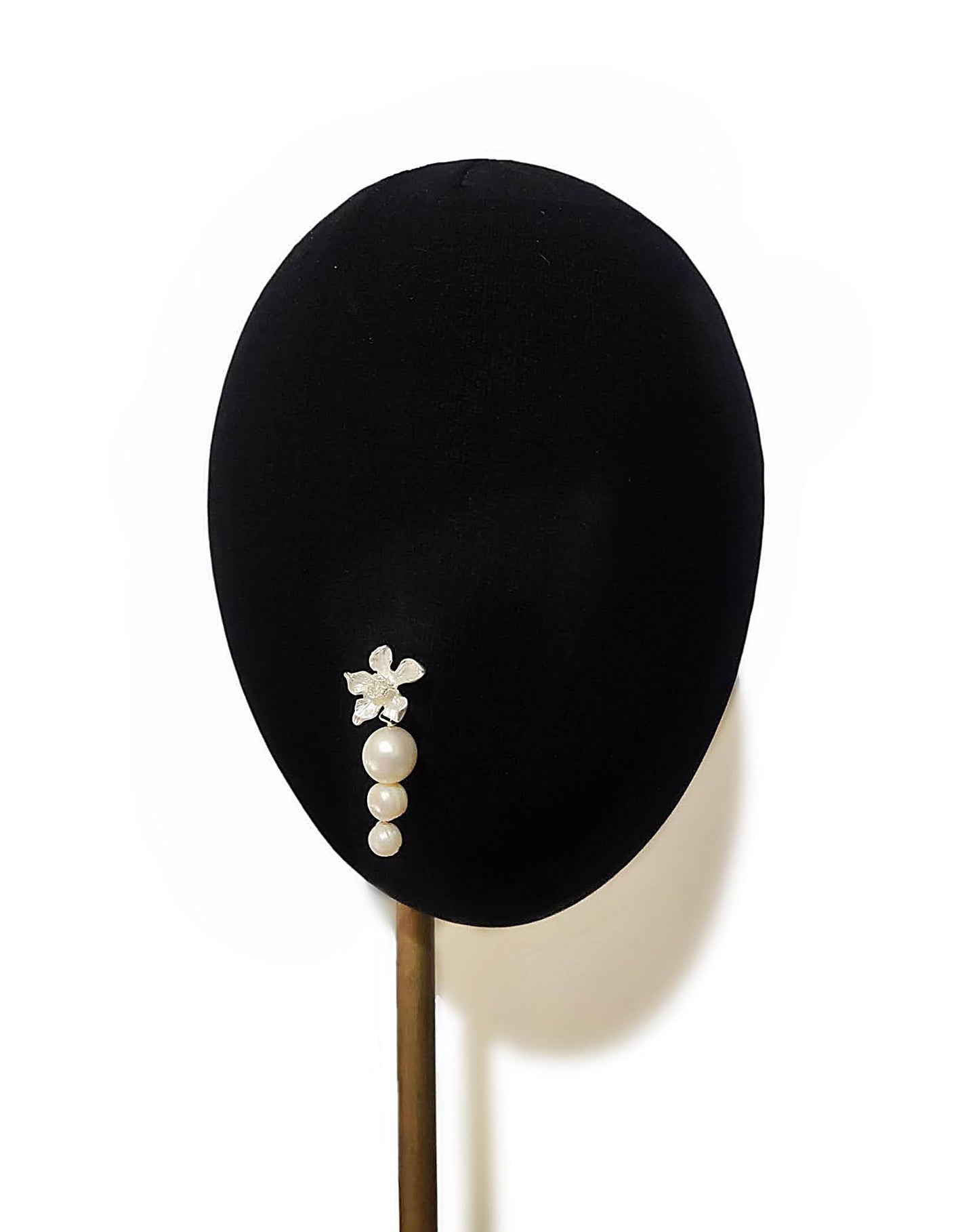 Perfil de cabeza de maniquí mostrando un pendiente dorado con flor y perlas de agua dulce.