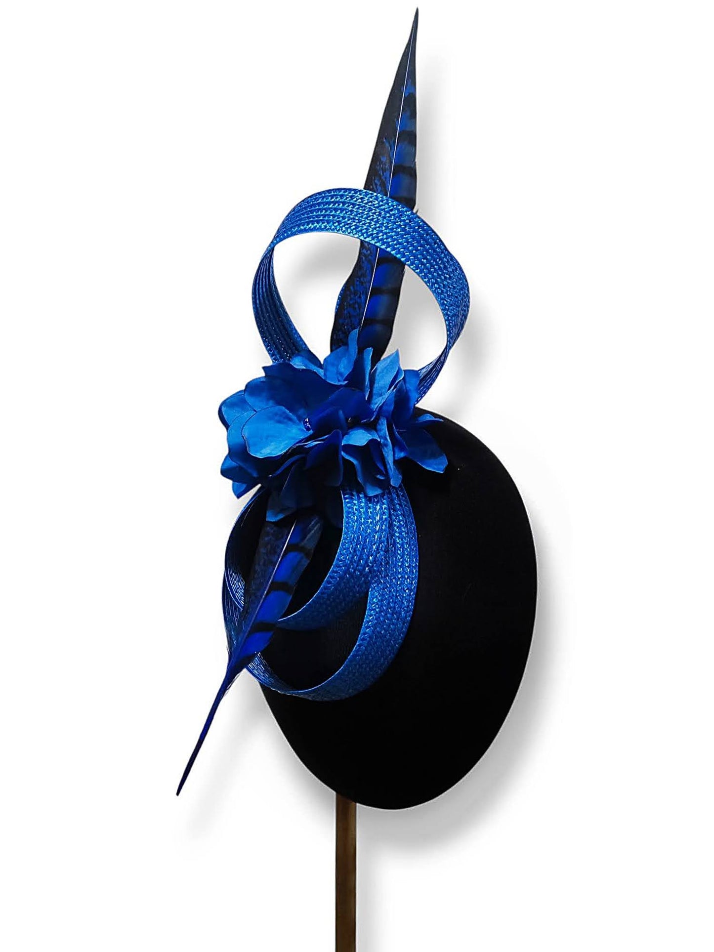 Vista de medio perfil derecho del tocado azul royal con flores de seda y pluma de faisán, mostrando su diseño ligero.