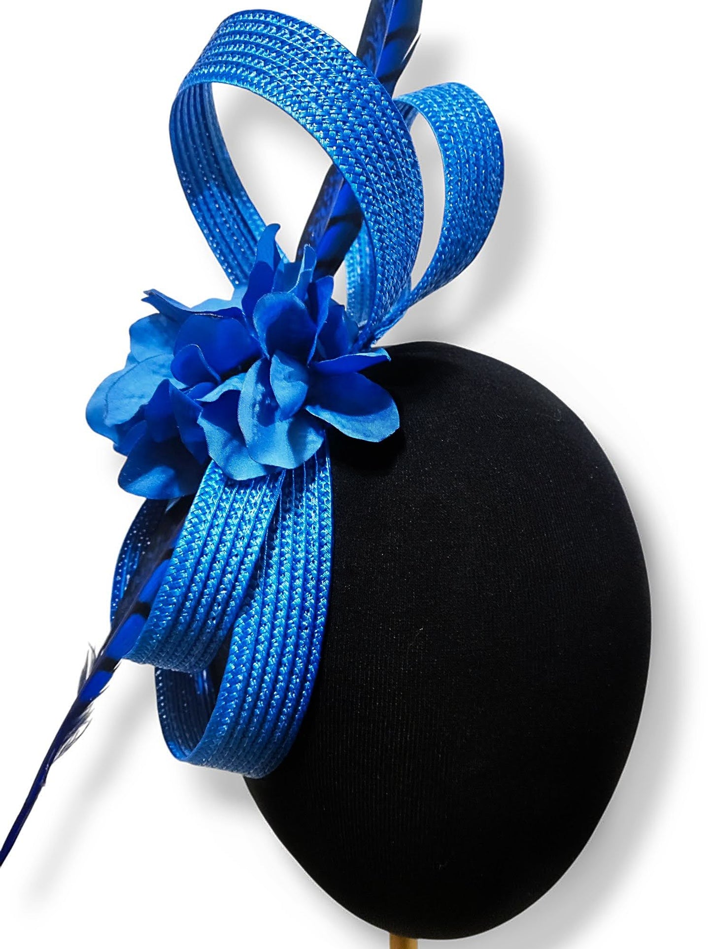 Primer plano del tocado azul royal, detallando las flores de seda y la pluma de faisán.