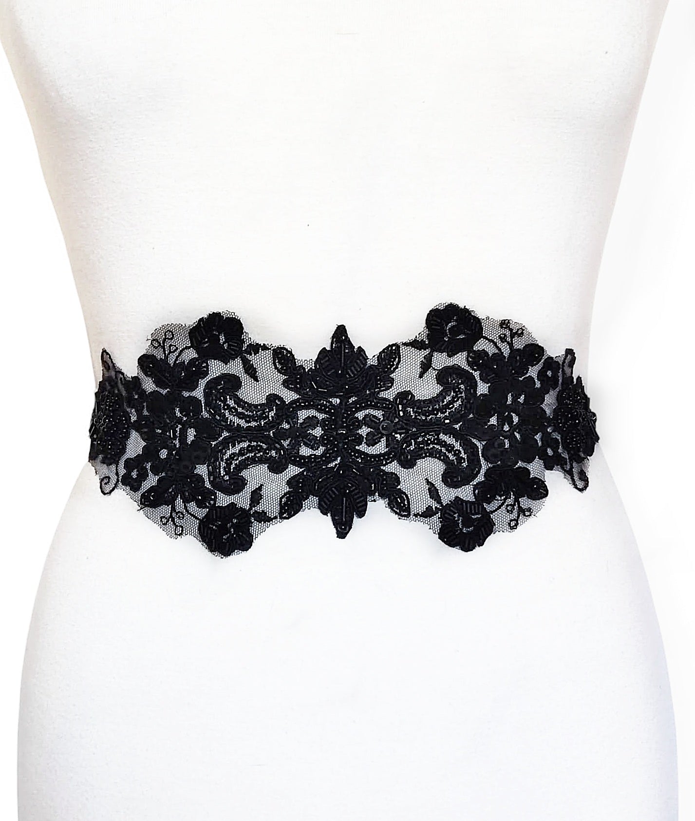 Vista frontal del fajín negro ancho de encaje bordado con cristal sobre maniquí.