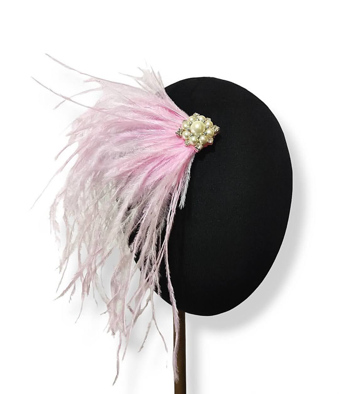 Tocado con plumas rosas y broche decorativo de perlas y cristal.