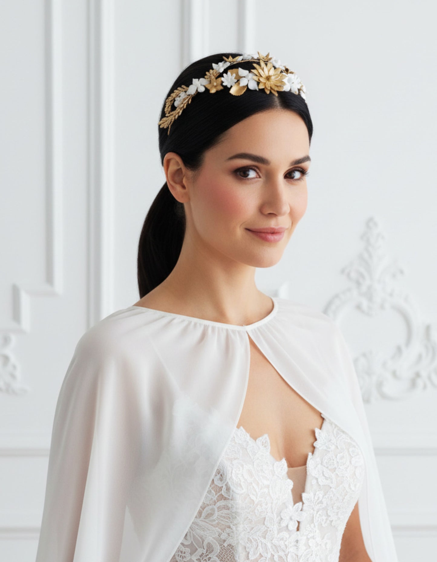 Braut trägt eine Tiara mit weißen und goldenen Porzellanblumen, mittig auf dem Kopf positioniert, kombiniert mit einem glatten, tiefen Pferdeschwanz. Handgefertigtes Design von Glo&Sons.