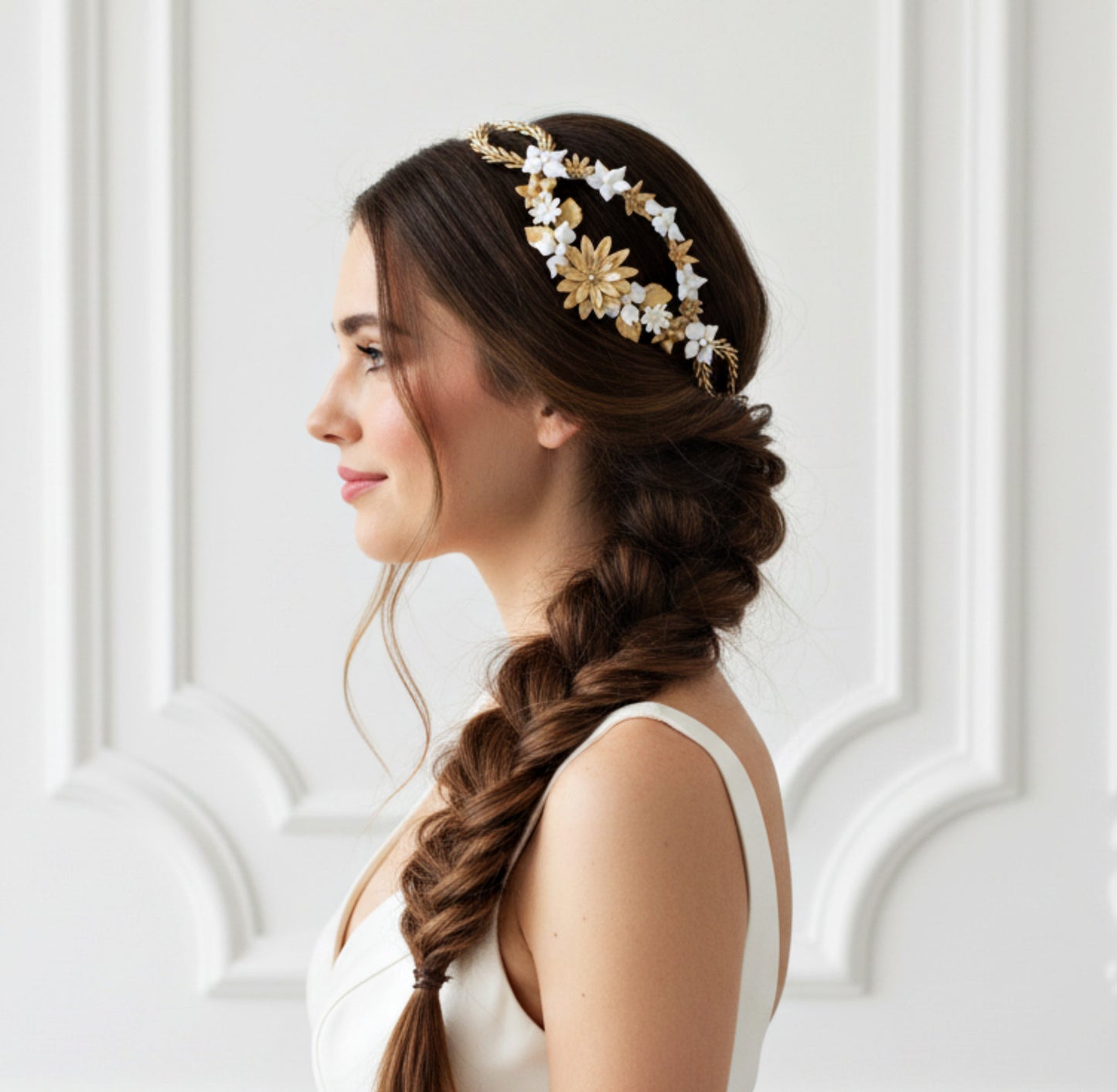 Bride wearing a side porcelain flower headpiece in white and gold tones, styled with a loose braid hairstyle. Handmade design by Glo&Sons