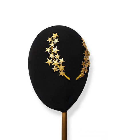 Primer plano de dos peinetas de estrellas doradas en porcelana fría sobre un soporte negro para resaltar el tono metalizado