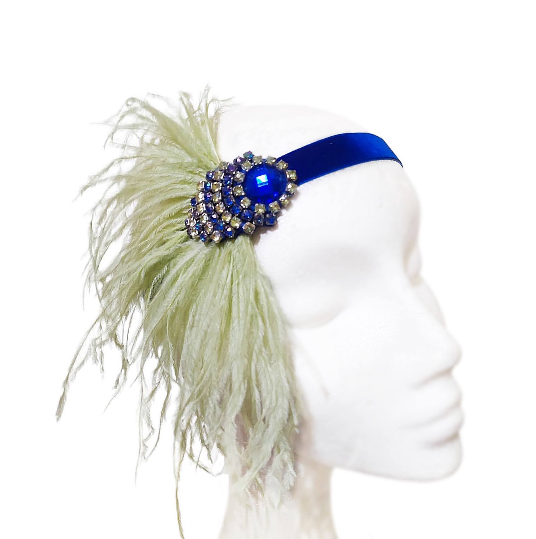 Vista medio perfil de diadema Gatsby donde se aprecia la banda de terciopelo azul cobalto y la caída de las plumas verde pistacho.