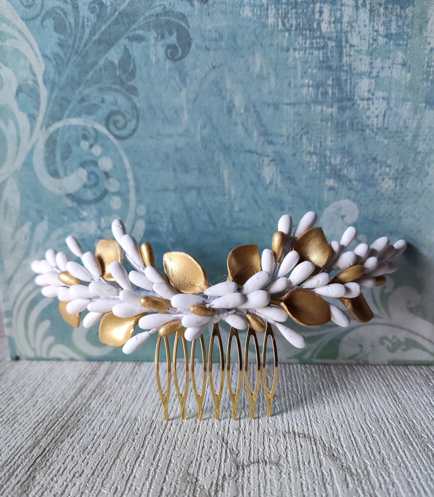 Peigne de mariée décoratif avec pistils et feuilles en porcelaine blanche et dorée, monté sur un peigne doré. Accessoire artisanal idéal pour compléter une coiffure de mariage. Glo&Sons