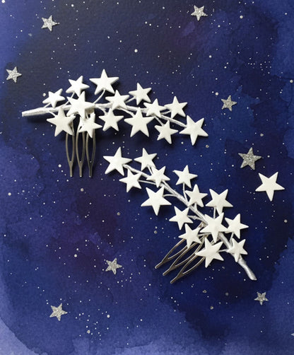 Pareja de peinetas de estrellas en porcelana fría blanca sobre un fondo artístico azul noche.