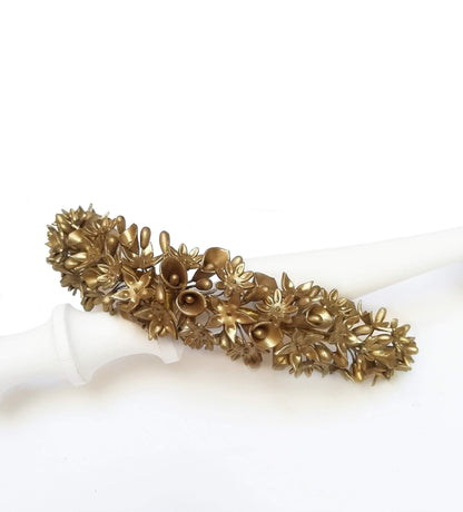 Tiara de flores de porcelana en color bronce sobre fondo blanco, mostrando la composición detallada y simétrica de la pieza artesanal.