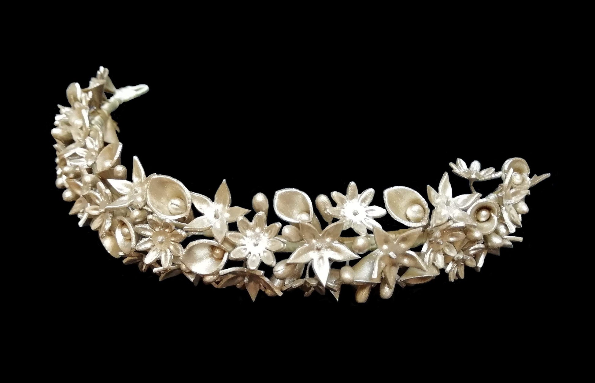 Tiara de flores de porcelana fría en color marfil sobre fondo oscuro para resaltar el tono crema natural y los detalles de los pistilos.
