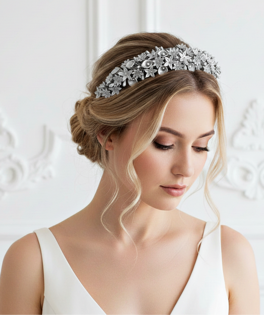 Novia con recogido bajo romántico luciendo una tiara de porcelana fría con mini flores plateadas y pistilos detallados.