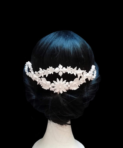 Tiara posteriore da sposa in porcellana bianca, decorata con fiori e foglie delicate, indossata con uno chignon elegante. Design artigianale realizzato a mano da Glo&Sons