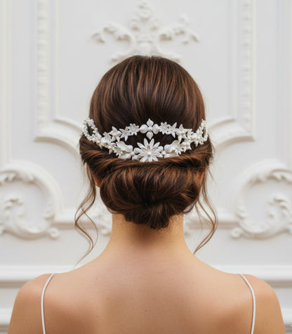 Tocado trasero de novia en blanco nacarado con flores y hojas de porcelana colocado sobre un elegante recogido bajp